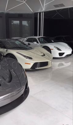 three different colored sports cars in a showroom with white and black paint on the walls