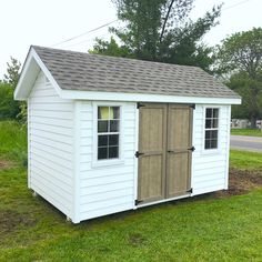 a white shed sitting on top of a lush green field