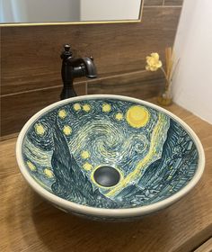 a bathroom sink with an artistic painting on it's bowl and faucet