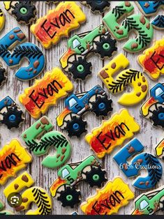 decorated cookies with cars and trucks are displayed on a wooden surface, including the word evan