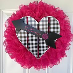 a heart shaped wreath with an arrow and name on it, hanging from the front door