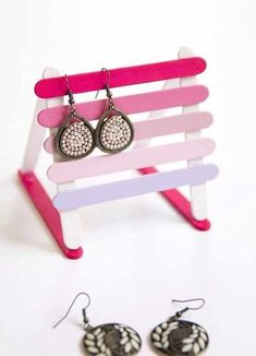 a pair of earrings sitting on top of a pink and white bench