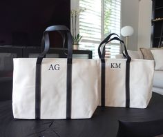 two bags sitting on top of a black table next to a white couch in front of a window