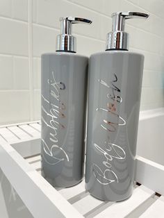 two gray soap dispensers sitting on a white shelf