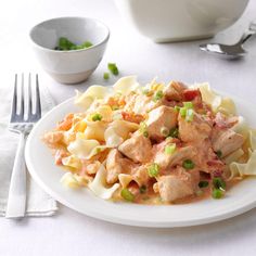 a white plate topped with pasta covered in meat and veggies next to a bowl of peas