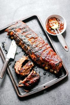 ribs and sauce on a tray with a knife