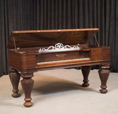 an old piano sitting in front of a curtain