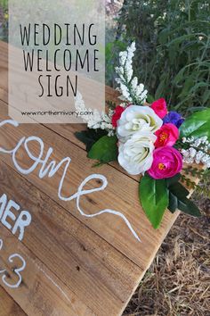 a wooden welcome sign with flowers on it