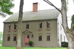 a large house with an american flag on the front door and two trees in front of it