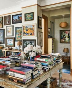 a living room filled with lots of books on top of a wooden table covered in pictures