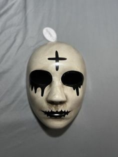 a white mask with black eyes and cross painted on it