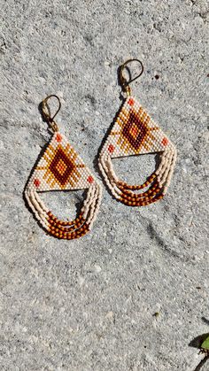 Hand beaded, patterned earrings in a triangle with dangle fringe. Brown Dangle Beaded Earrings For Summer, Summer Brown Tassel Jewelry, Summer Brown Beaded Earrings, Bohemian Teardrop Beaded Fringe Jewelry, Summer Beaded Fringe Chandelier Earrings, Adjustable Triangle Beaded Earrings, Traditional Beaded Fringe Earrings For Summer, Festival Jewelry With Beaded Fringe, Bohemian Triangle-shaped Jewelry For Festivals