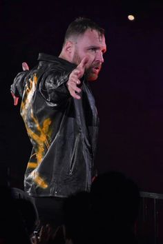 a man in a leather jacket standing on stage