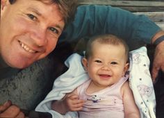 a man holding a baby in his arms and smiling at the camera with another person next to him