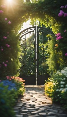 an open gate with flowers surrounding it and the sun shining through from behind in the background