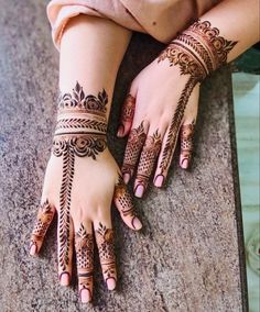 a woman's hands with henna tattoos on her arm and hand, sitting on the ground