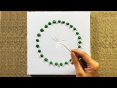 a hand is holding a needle and string in the shape of a clock made out of green beads