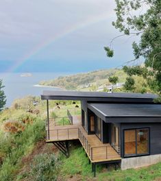 a small house with a rainbow in the sky above it and some grass on the ground