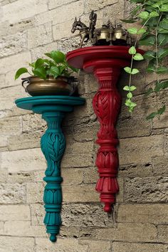 two red and green planters on the side of a brick wall next to a potted plant