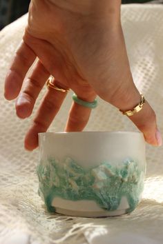 a woman's hand reaching into a white and green cup