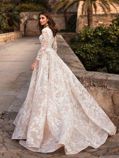 a woman in a wedding dress standing on a stone walkway with palm trees behind her