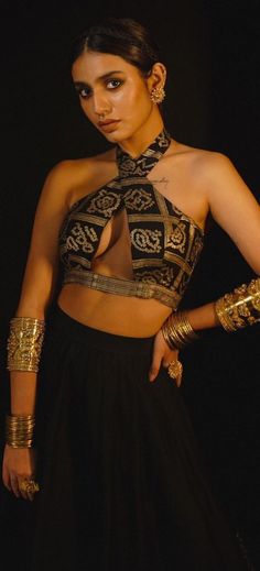 a woman in a black and gold outfit with her hands on her hips, posing for the camera