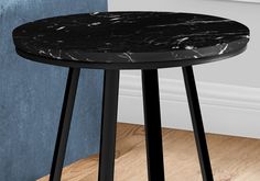 a black marble topped table sitting on top of a hard wood floor next to a blue wall