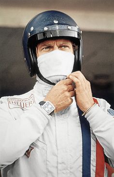 a man wearing a helmet and holding his face mask to his mouth as he adjusts it