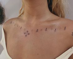 the back of a woman's shoulder with small tattoos on her upper arm and chest