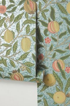 the wall paper has fruit on it and is blue with green leaves, oranges and pink flowers