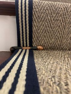 a close up of a striped rug on the floor next to a stair case with a wooden handle