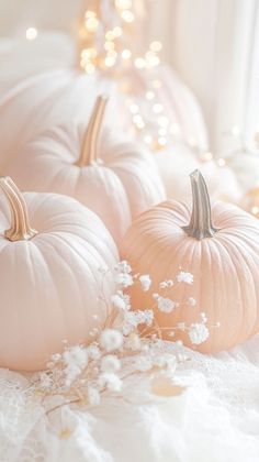 three white pumpkins sitting on top of a bed next to a window sill