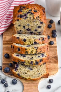 slices of blueberry banana bread on a cutting board with fresh blueberries around it