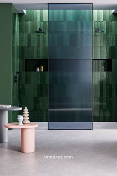 a bathroom with green tiles on the walls and floor, along with a round table