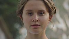 a close up of a person wearing a necklace and earrings with trees in the background