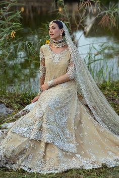 a woman sitting on the ground wearing a wedding dress with long sleeves and a veil