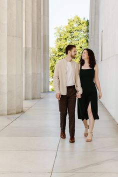 an engaged couple walking through the lincoln memorial