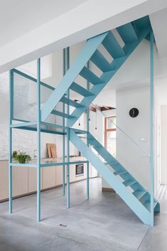 a blue stair case in the middle of a room with white walls and flooring