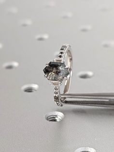 a diamond ring sitting on top of a silver surface with drops of water around it