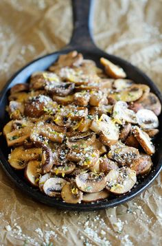 a skillet filled with mushrooms and seasoning on top of a wooden tablecloth