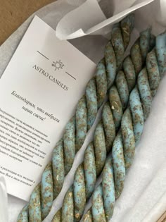 blue and gold speckled beads are on display in a white box with a paper