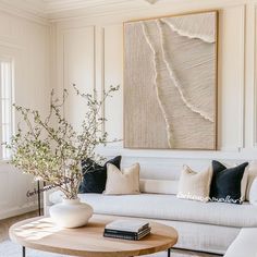 a living room filled with furniture and a large painting on the wall above it's coffee table