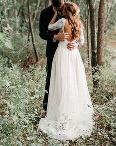 a bride and groom standing in the woods hugging each other with their arms around each other