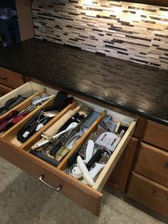 an open drawer in a kitchen filled with utensils