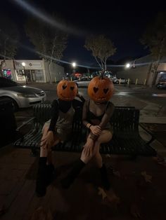 two people sitting on a bench with pumpkin heads