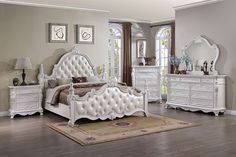 a bedroom with white furniture in it and hardwood floors, including a large mirror on the wall