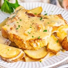 a white plate topped with meat covered in gravy next to potato wedges