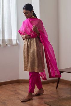 Chai anarkali with gold stripe woven motifs and zari embroidered neckline in floral pattern. Paired with hot pink cigarette fit pant.
Components: 2
Pattern: Woven, Embroidery
Type Of Work: Stripe, zari, floral
Neckline: V neck
Sleeve Type: Three quarter
Fabric: Kurta: Chanderi Tissue Stripe, Pant: Banglore Silk, Lining: Shantoon
Color: Brown,Pink
Other Details: 
Side pockets on kurta
Embroidered neckline
Elasticated waistband
Length:
Kurta: 38 inches
Pant: 36 inches
Model height: 5ft 9inches, we Unstitched Anarkali Palazzo Set In Gold, Unstitched Gold Anarkali Palazzo Set, Gold Anarkali Palazzo Set With Traditional Drape, Gold Anarkali-style Palazzo Set, Festive Gold Palazzo Set Traditional Drape, Festive Gold Palazzo Set With Dupatta, Festive Gold Anarkali Palazzo Set, Designer Gold Slub Silk Kurta, Gold Chanderi Palazzo Set For Navratri