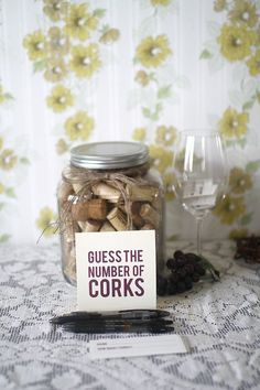 a glass jar filled with lots of corks next to a note that says guess the number of corks