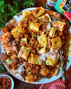 pasta with meat sauce and parmesan cheese on a plate next to seasoning